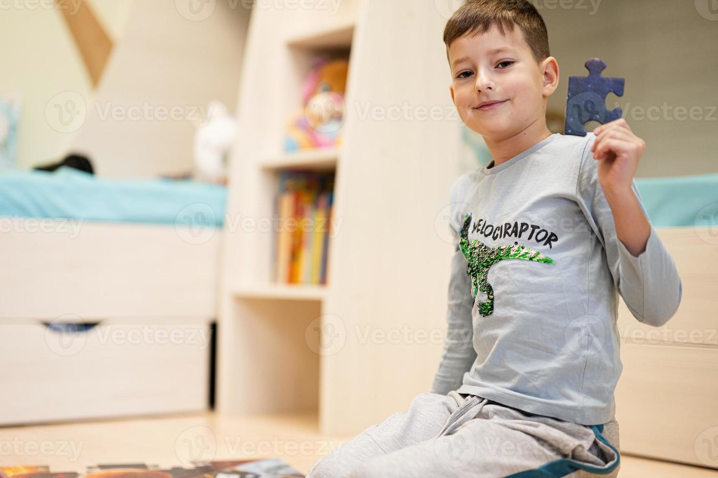 menino conectando peças de quebra-cabeça em um quarto de crianças no chão em casa. diversão em família atividade lazer. foto