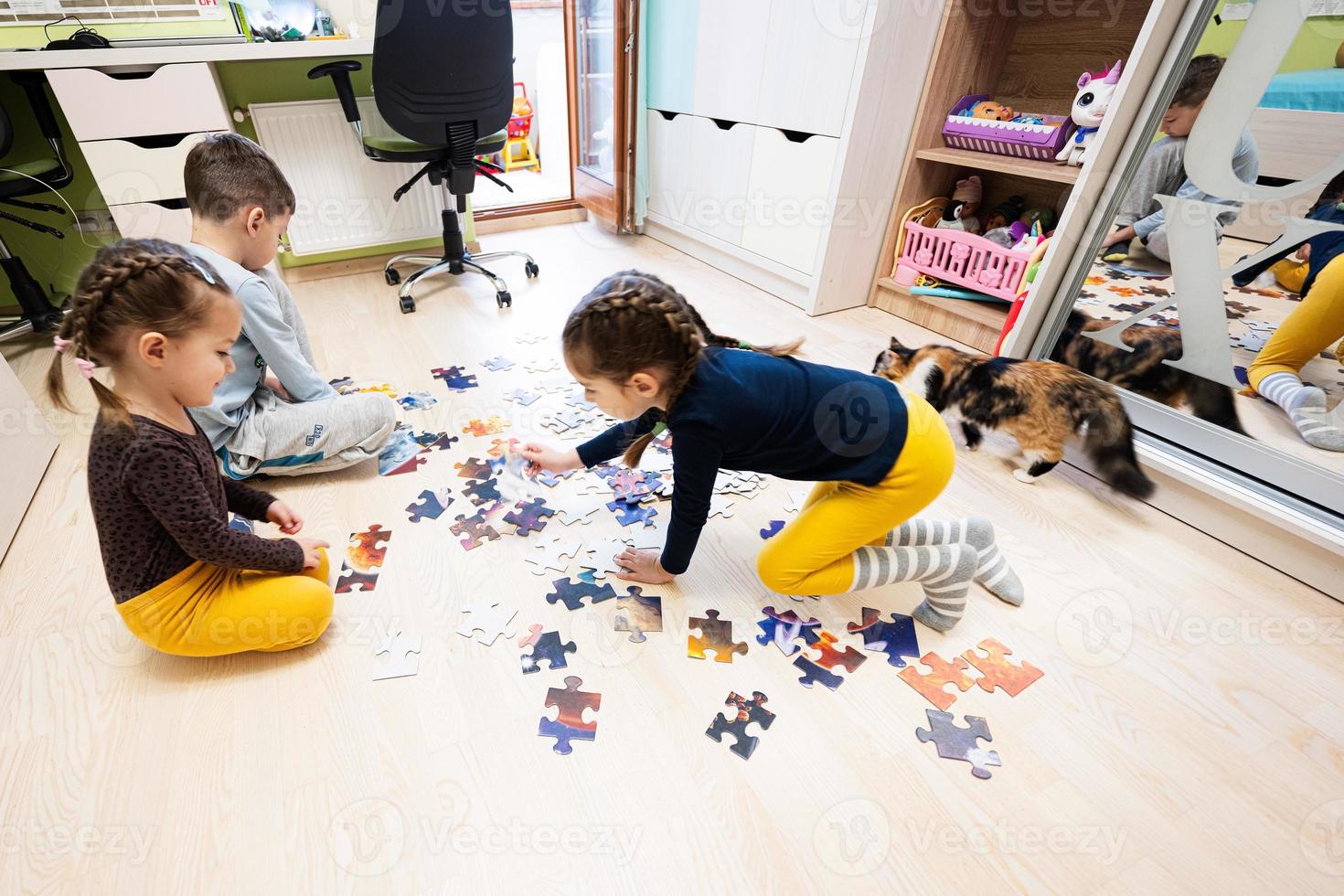 crianças conectando peças de quebra-cabeça em um quarto infantil no chão de casa. diversão em família atividade lazer. foto