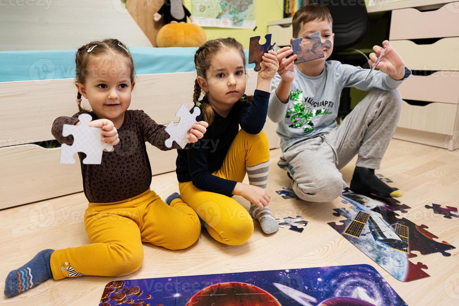 crianças conectando peças de quebra-cabeça em um quarto infantil no chão de casa. diversão em família atividade lazer. foto