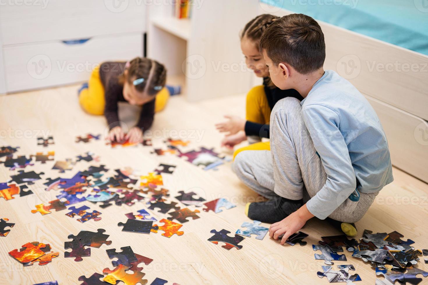 crianças conectando peças de quebra-cabeça em um quarto infantil no chão de casa. diversão em família atividade lazer. foto