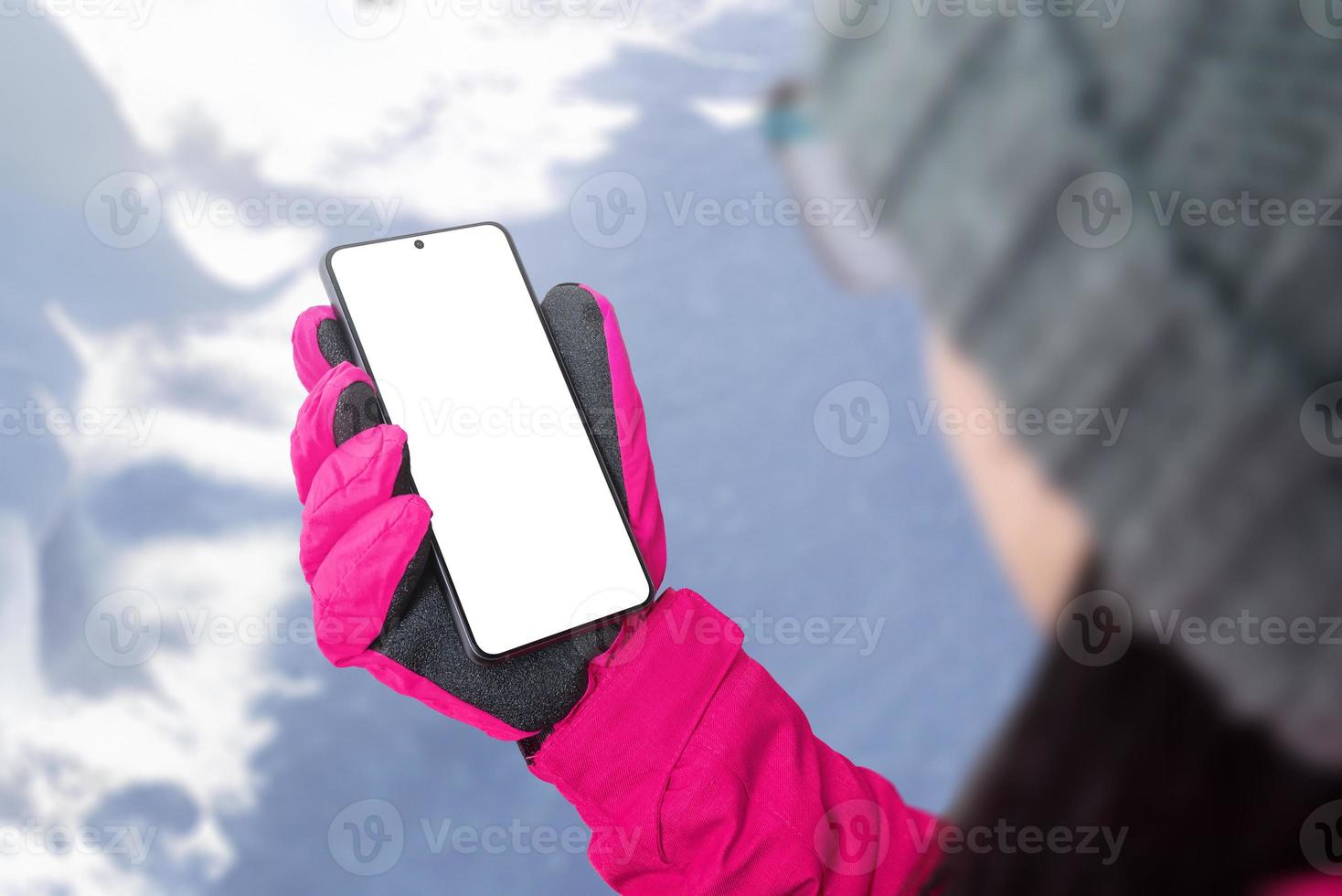 menina com chapéu, jaqueta e luvas está segurando um celular com uma tela isolada foto