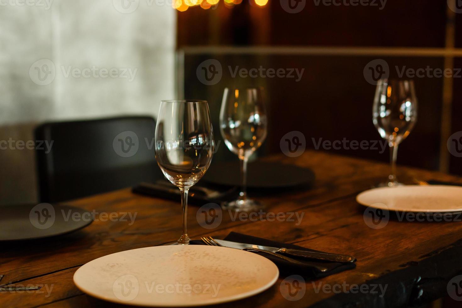 copos, garfos, facas, pratos em uma mesa no restaurante servido para jantar foto