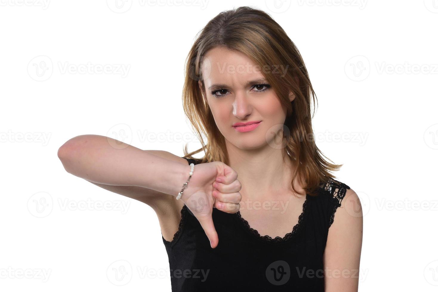 retrato de uma jovem mulher bonita espiando a câmera mostrando os polegares para baixo. isolado no branco foto