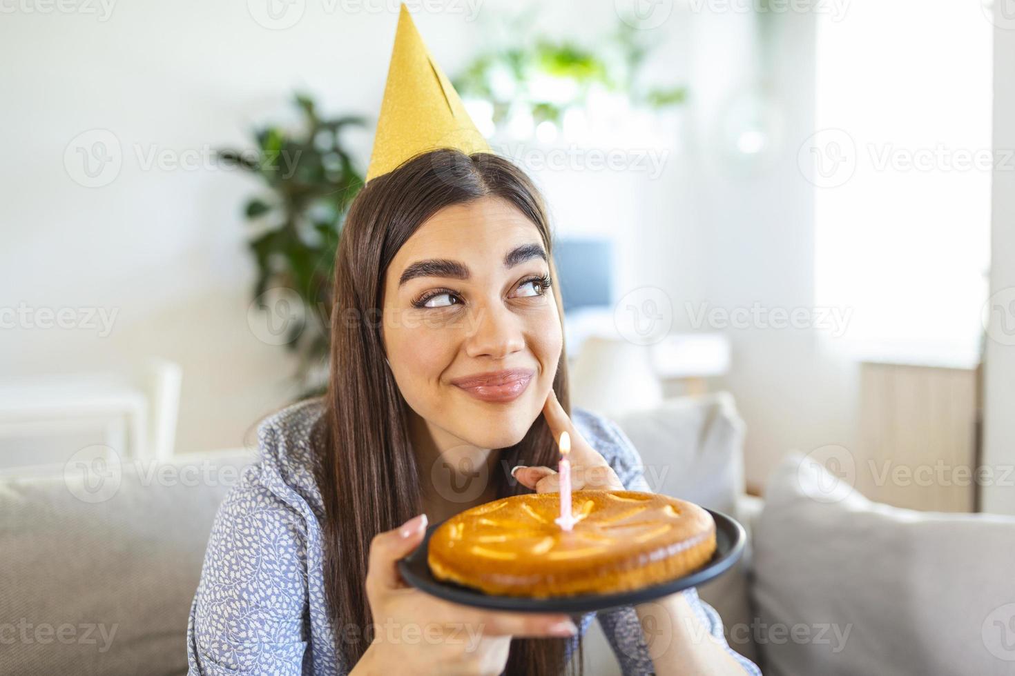 novo conceito normal. mulher feliz comemorando seu aniversário sozinha. jovem mulher segurando um bolo. festa de aniversário em casa. chamada de vídeo em família. distanciamento social. vida em casa. foto