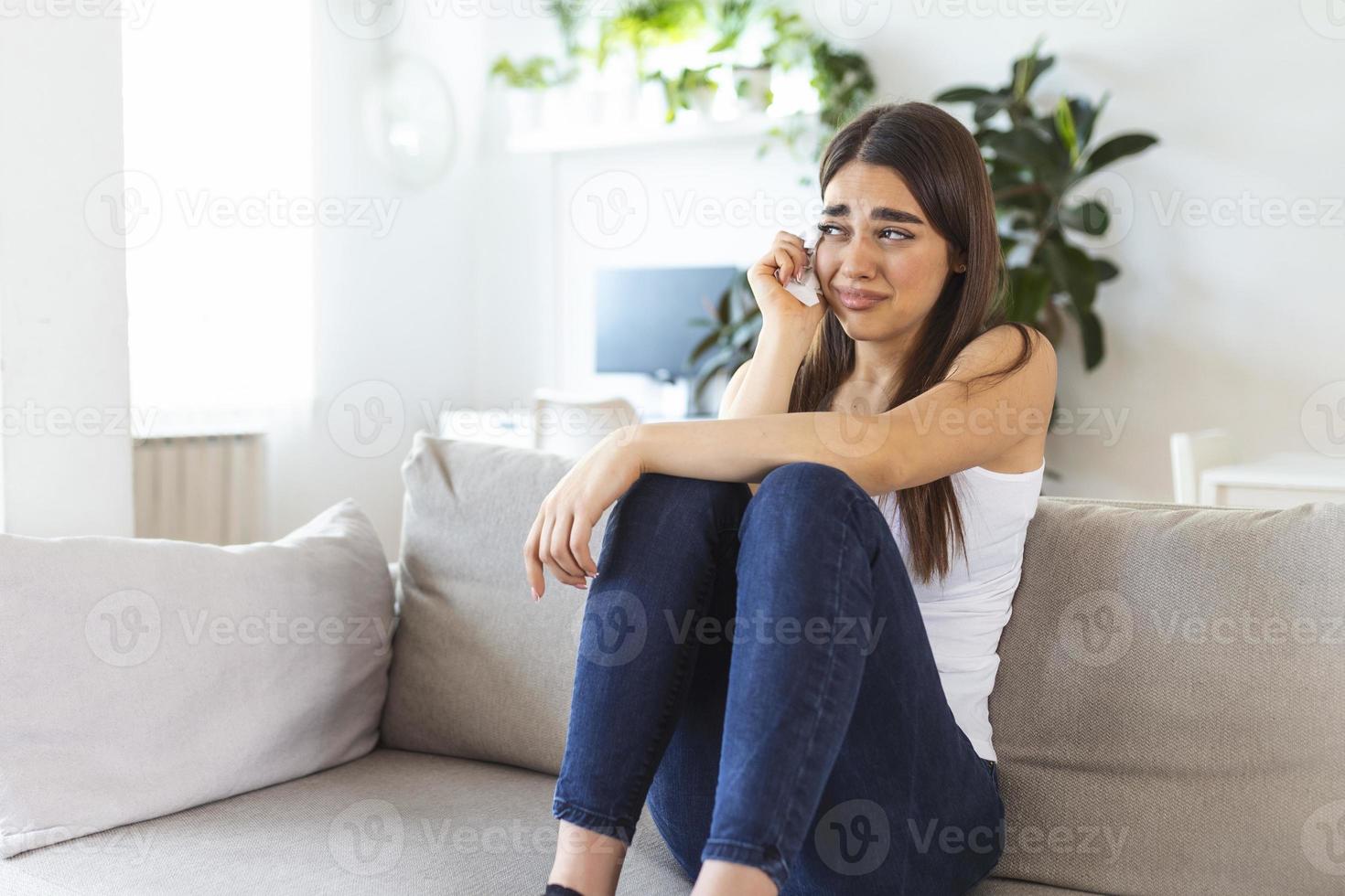 feche a jovem se sentindo chateada, triste, infeliz ou decepcionada chorando sozinha em casa. choque emocional e problemas de vida foto