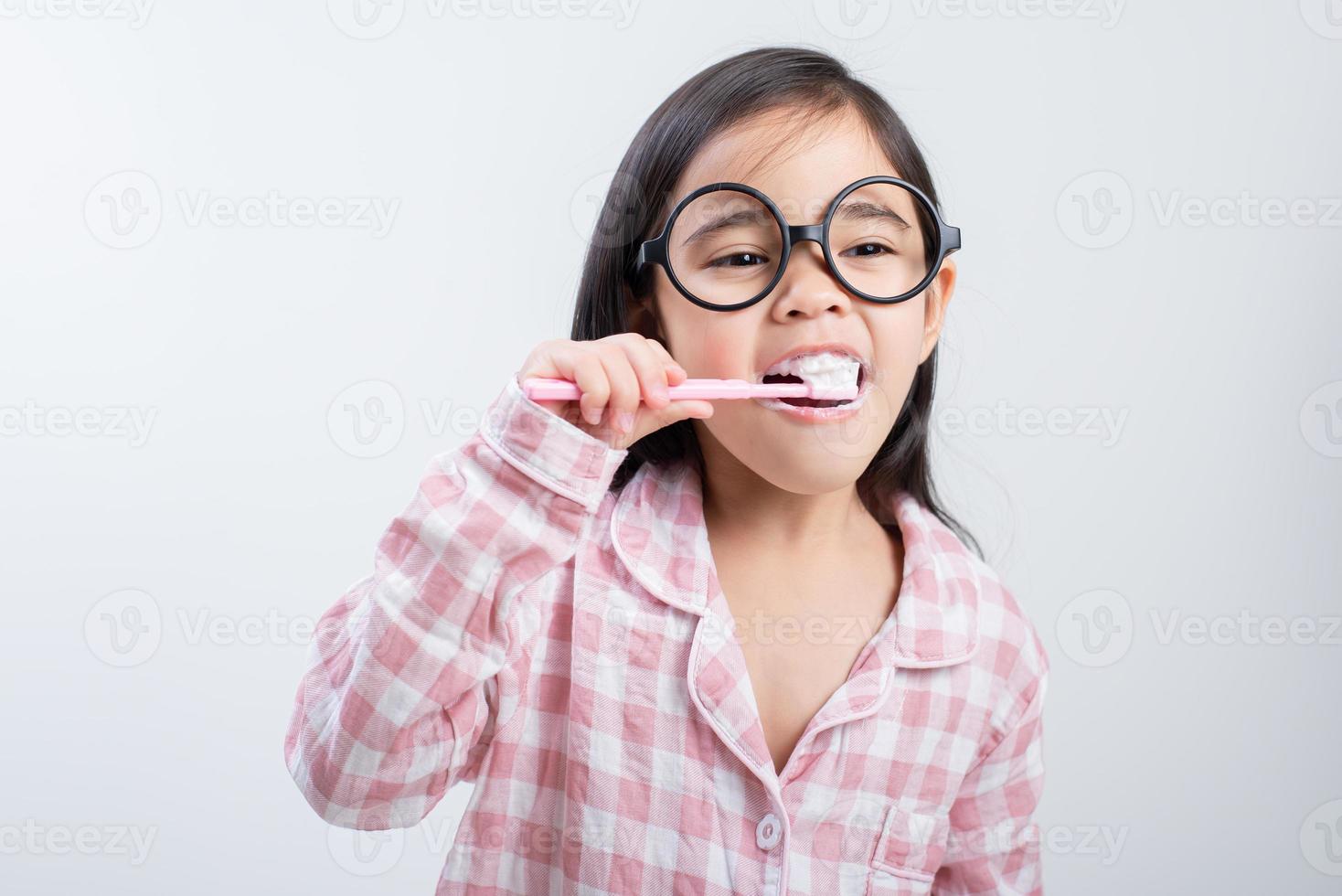 menina ásia escovando os dentes alegremente fundo branco foto