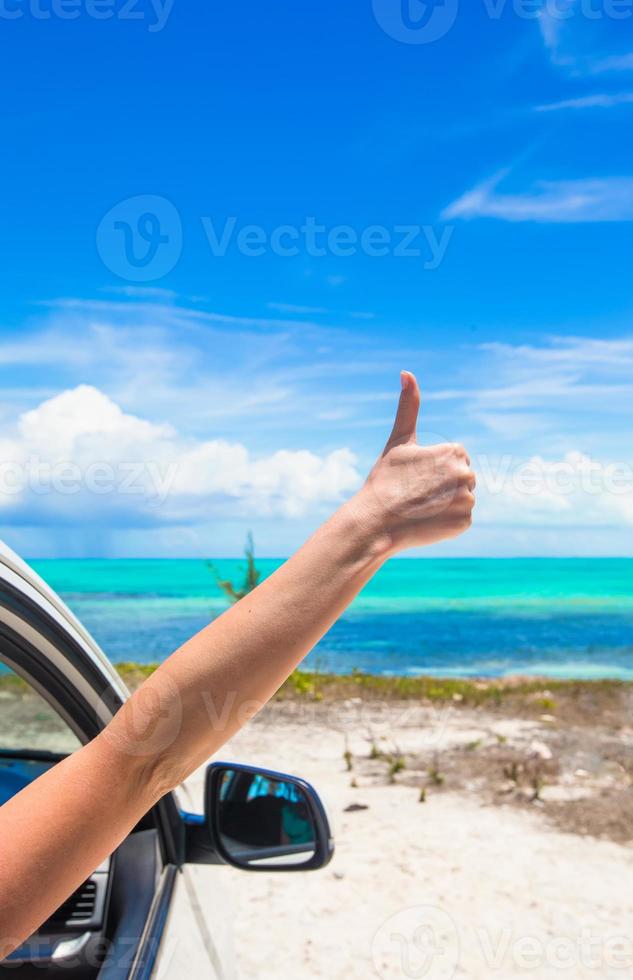 jovem mulher mostrando os polegares para cima na praia foto