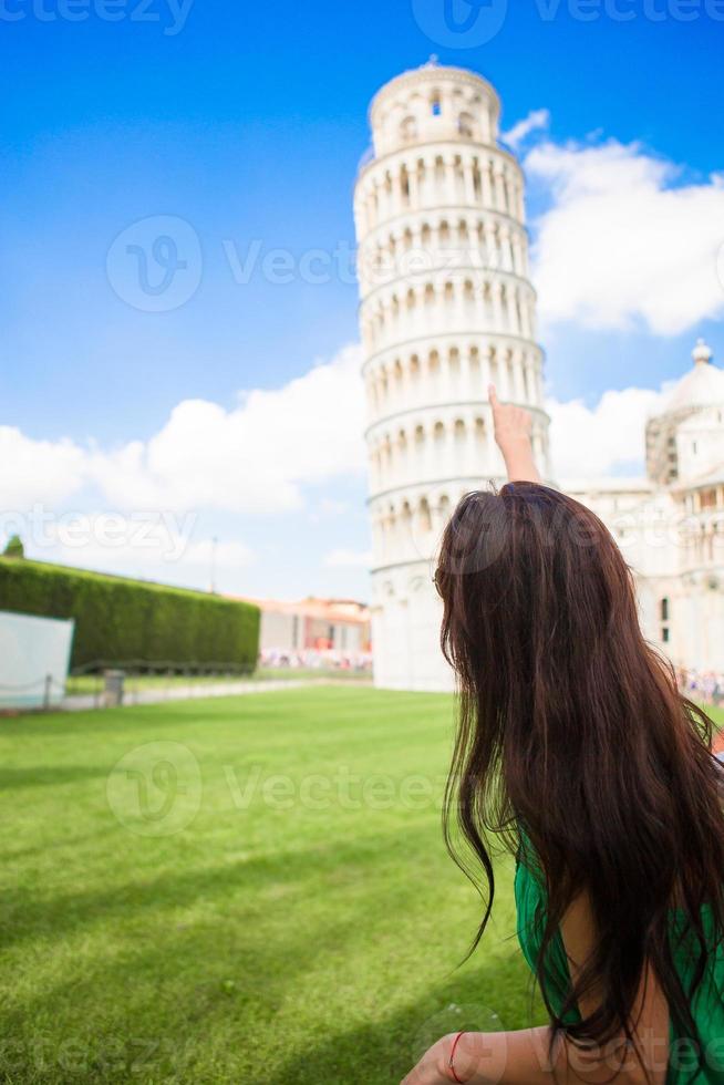vista traseira da mulher jovem turista olhando na torre inclinada de pisa. foto