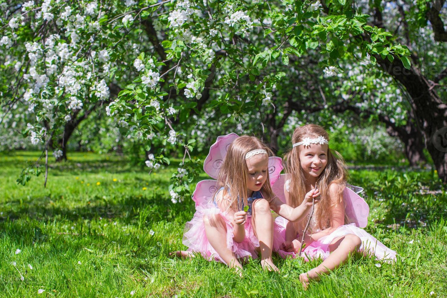 meninas adoráveis com asas de borboleta no pomar de maçã em flor foto