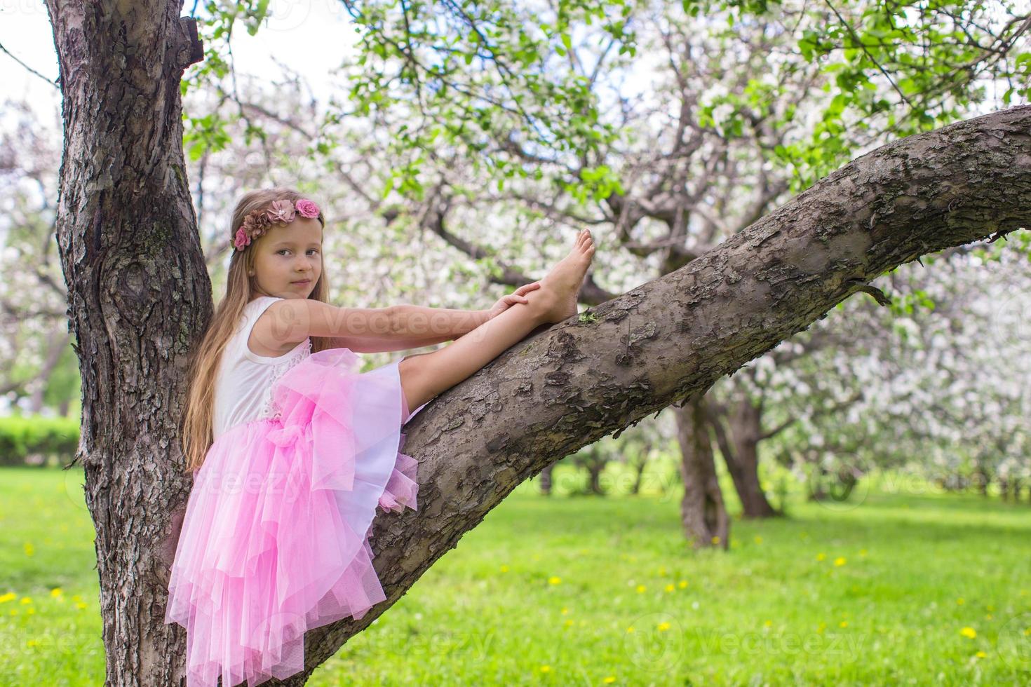 menina adorável sentada na macieira florescendo foto