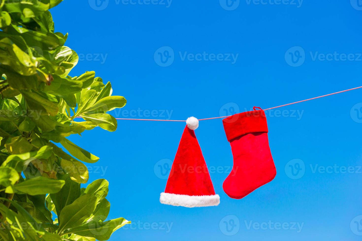 chapéu de papai noel vermelho e meia de natal entre palmeiras na praia branca foto