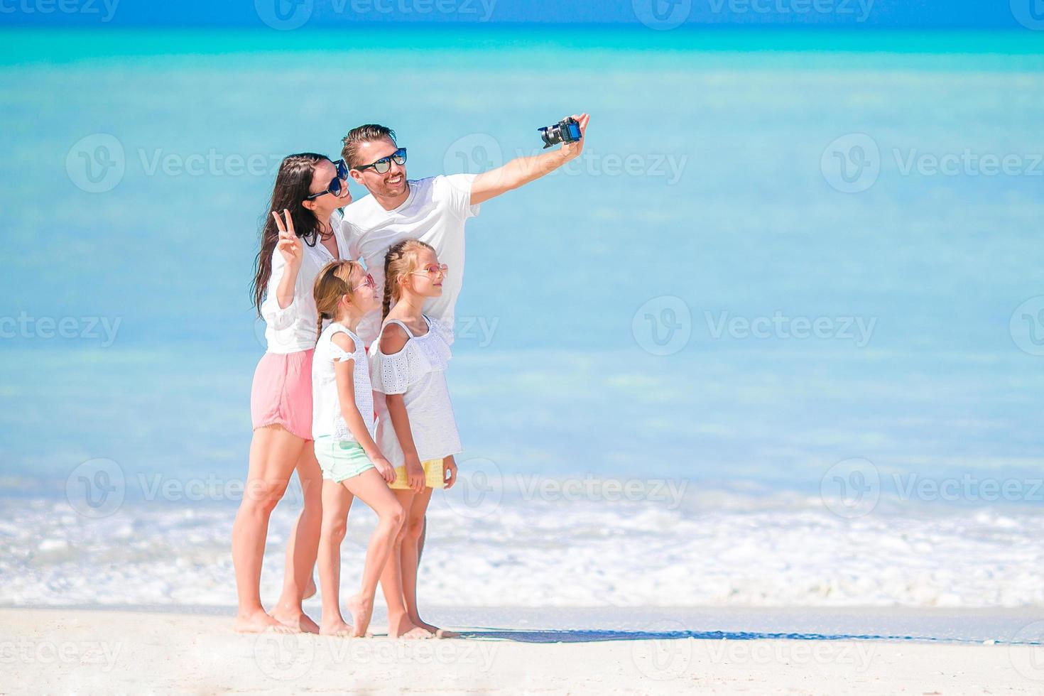 homem tirando uma foto de sua família na praia. férias com a família