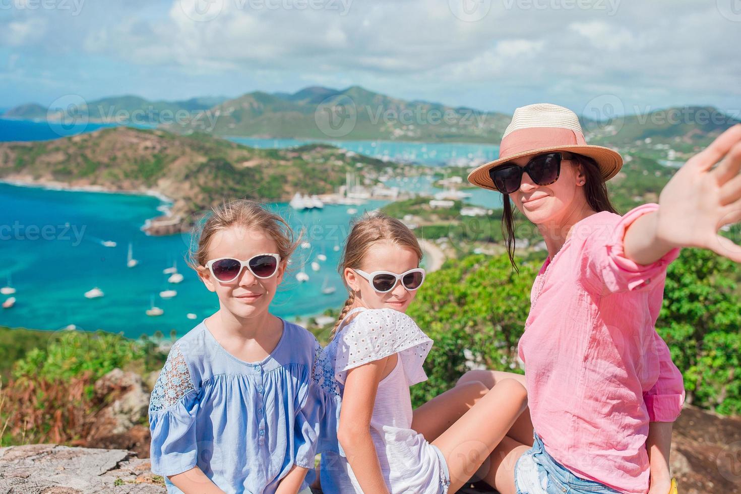 mãe e filhos tirando selfie com vista para o porto inglês de shirley heights, antígua, paradise bay na ilha tropical no mar do caribe foto