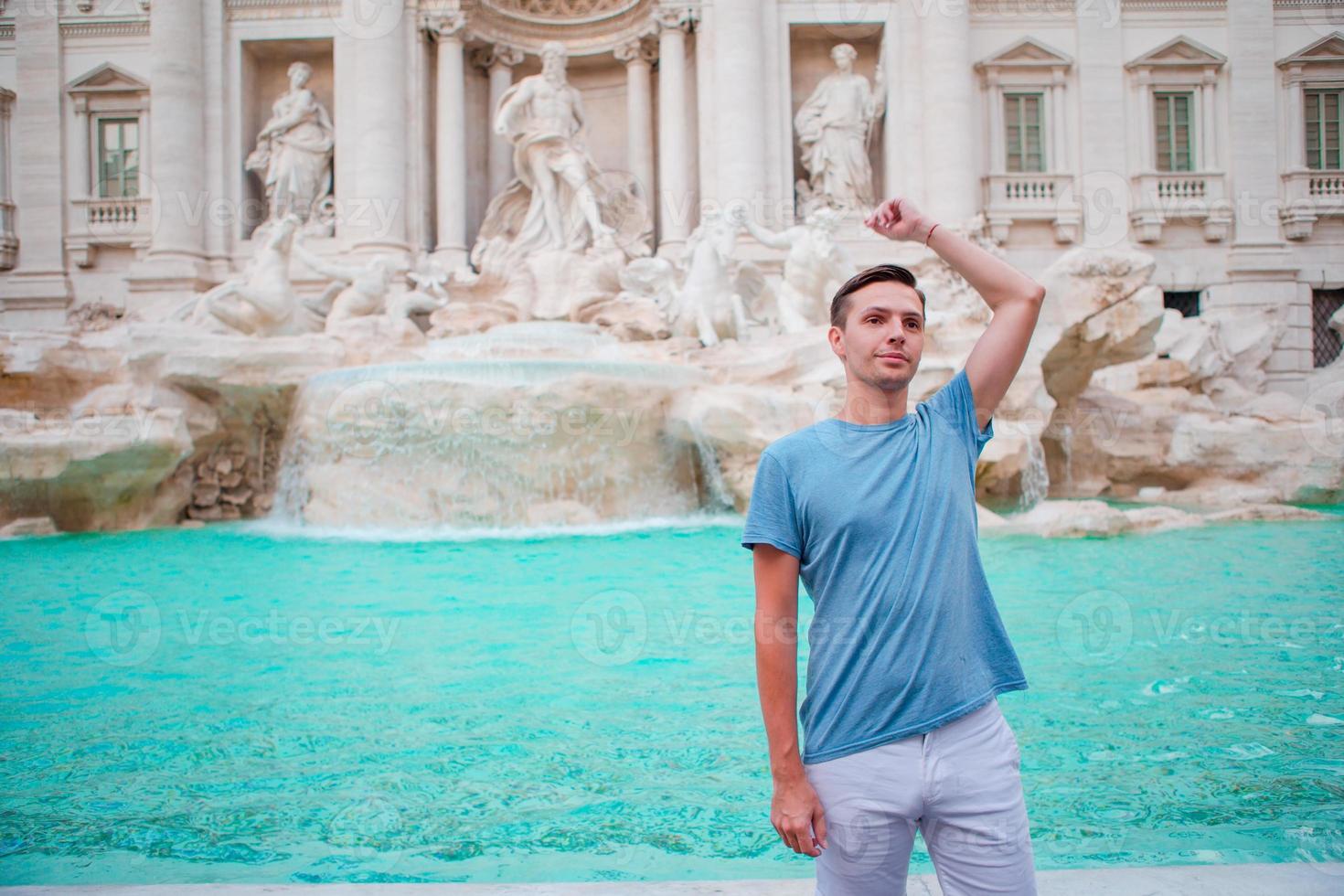 jovem turista jogando moedas na fonte de trevi, roma, itália para dar sorte. cara caucasiano fazendo um desejo de voltar. foto