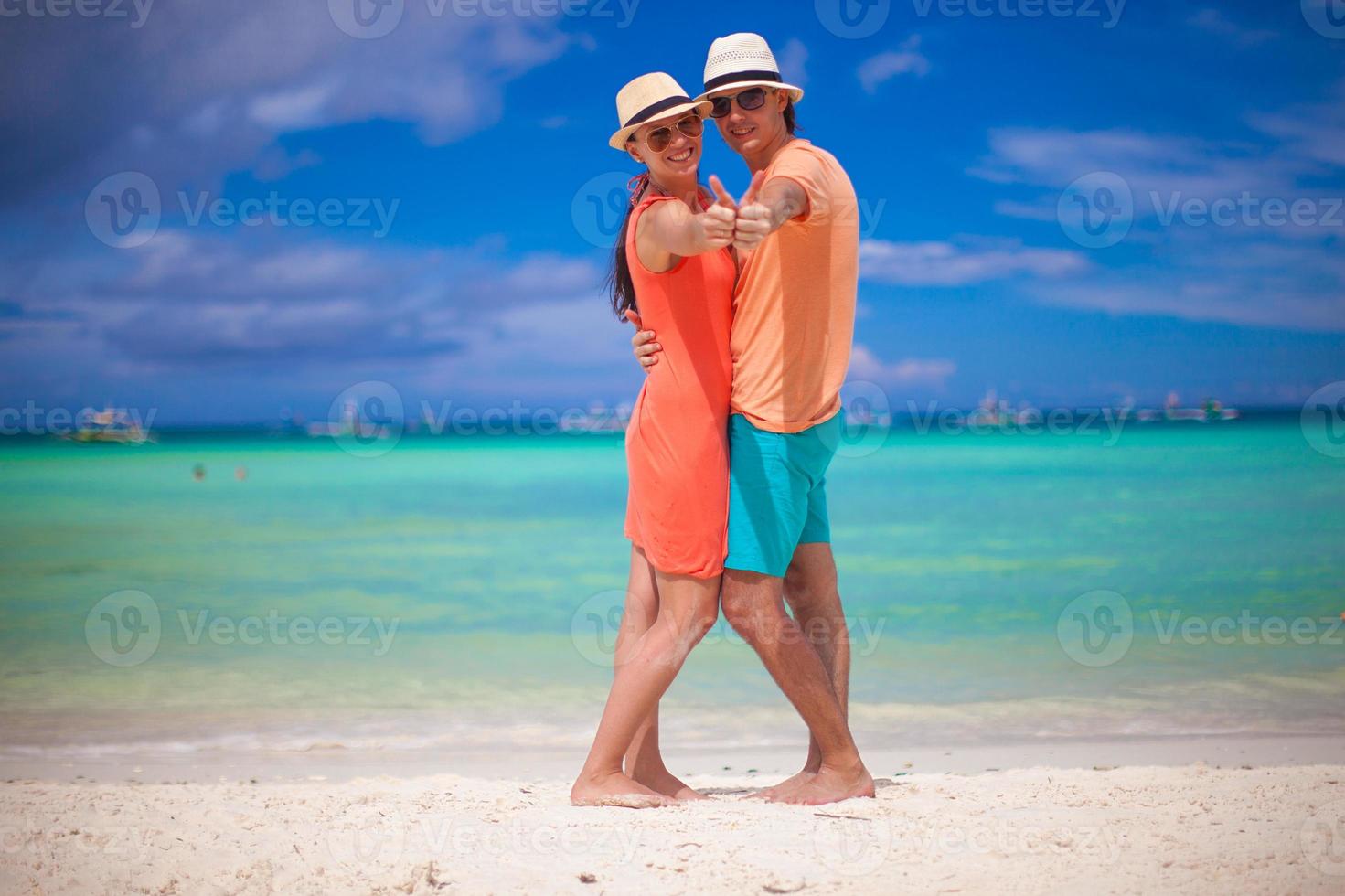 jovem casal lindo mostrando os polegares para cima na praia foto