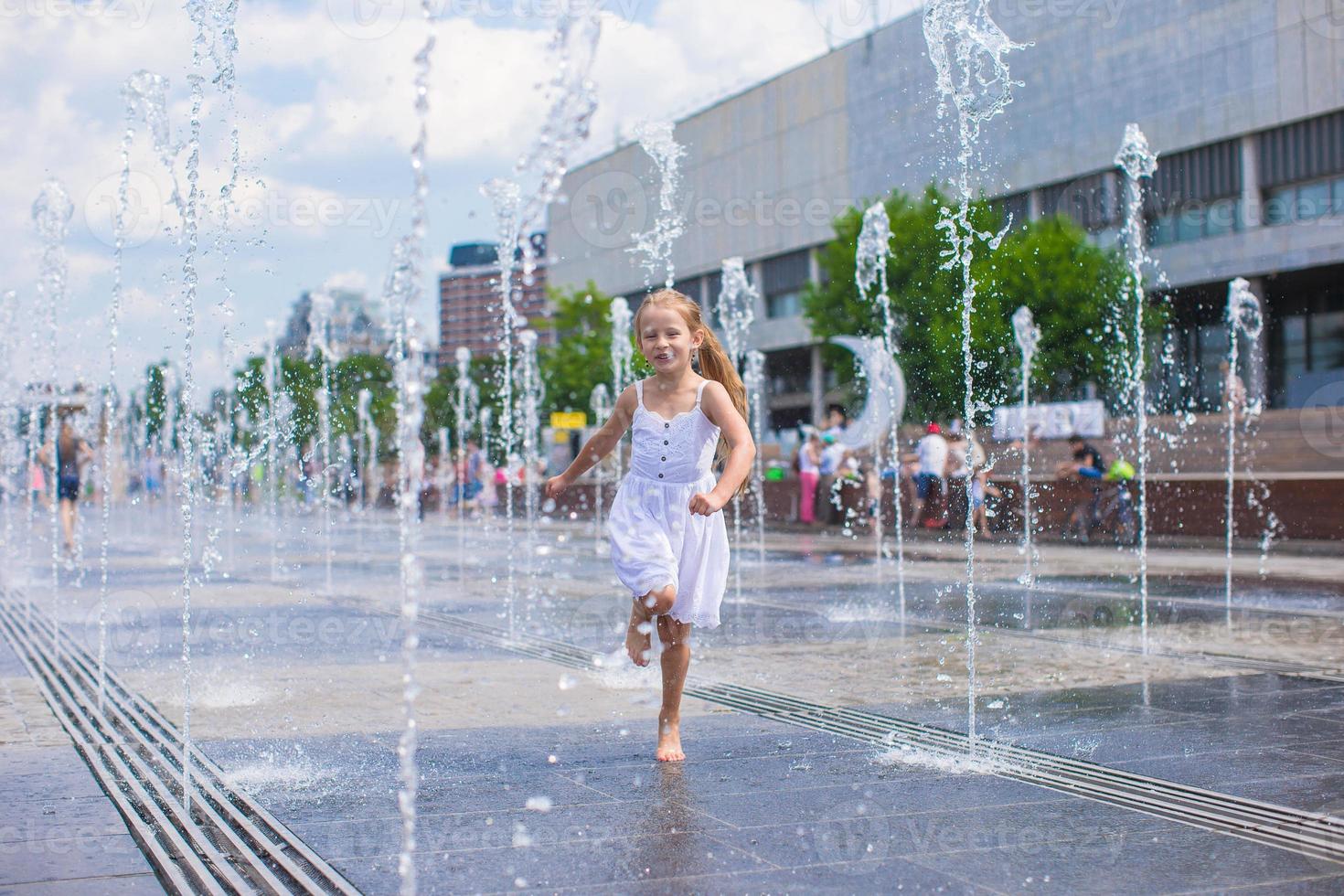 menina bonitinha andando na fonte de rua aberta no dia quente e ensolarado foto