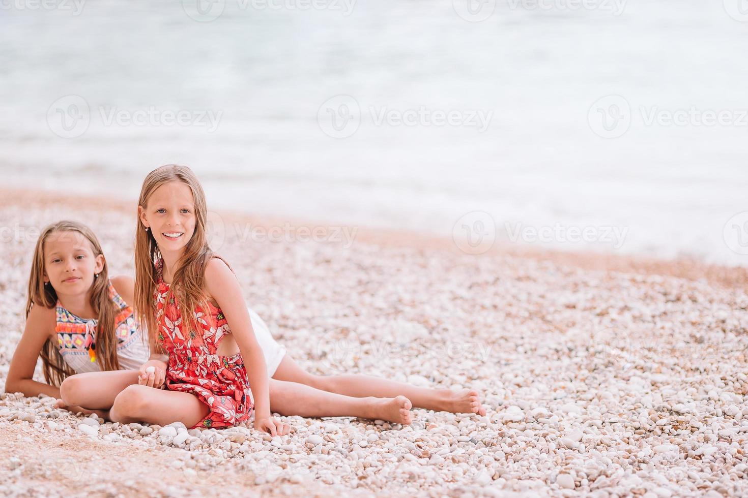 duas meninas felizes se divertem muito na praia tropical brincando juntas foto