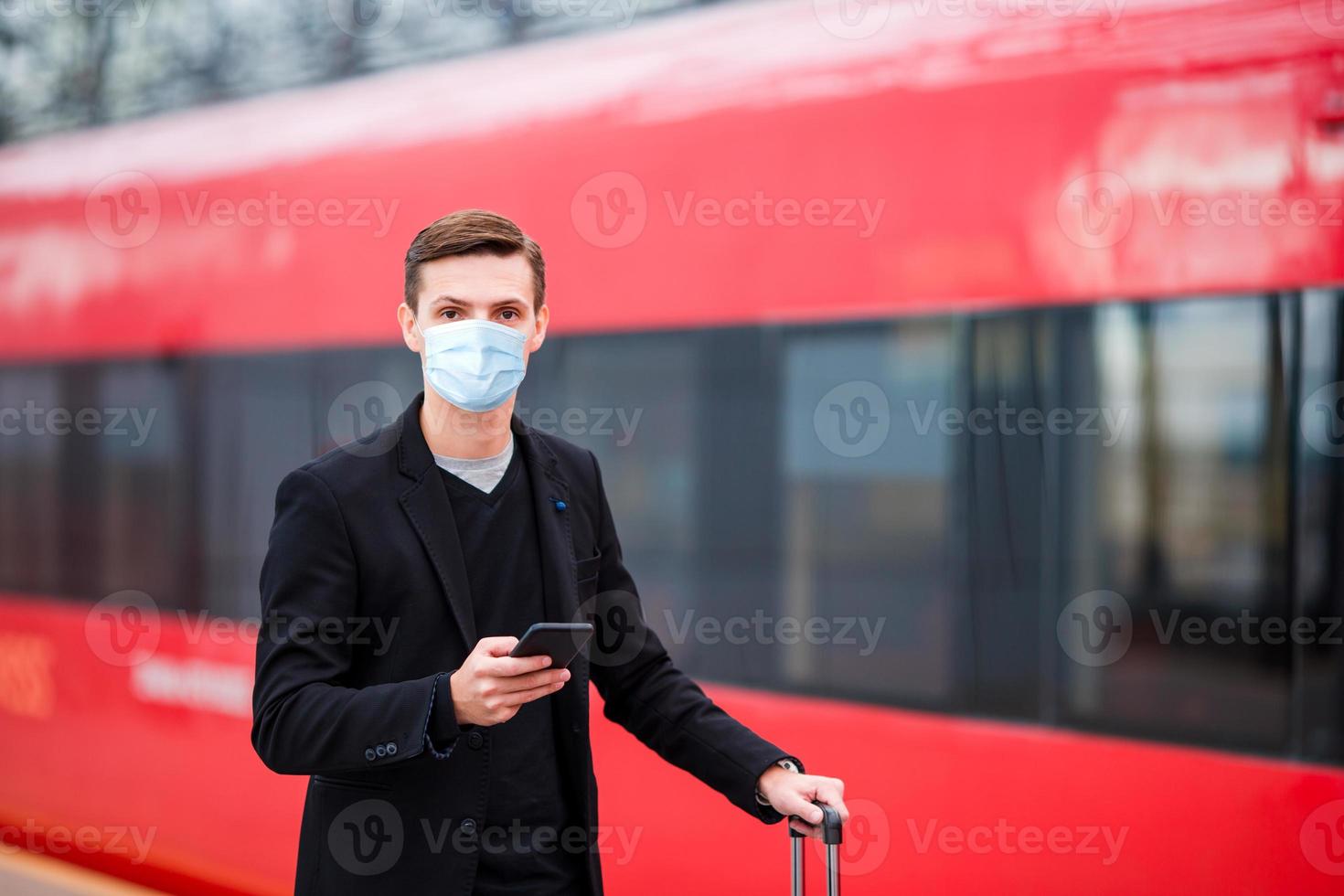 jovem turista com bagagem na plataforma esperando o trem foto