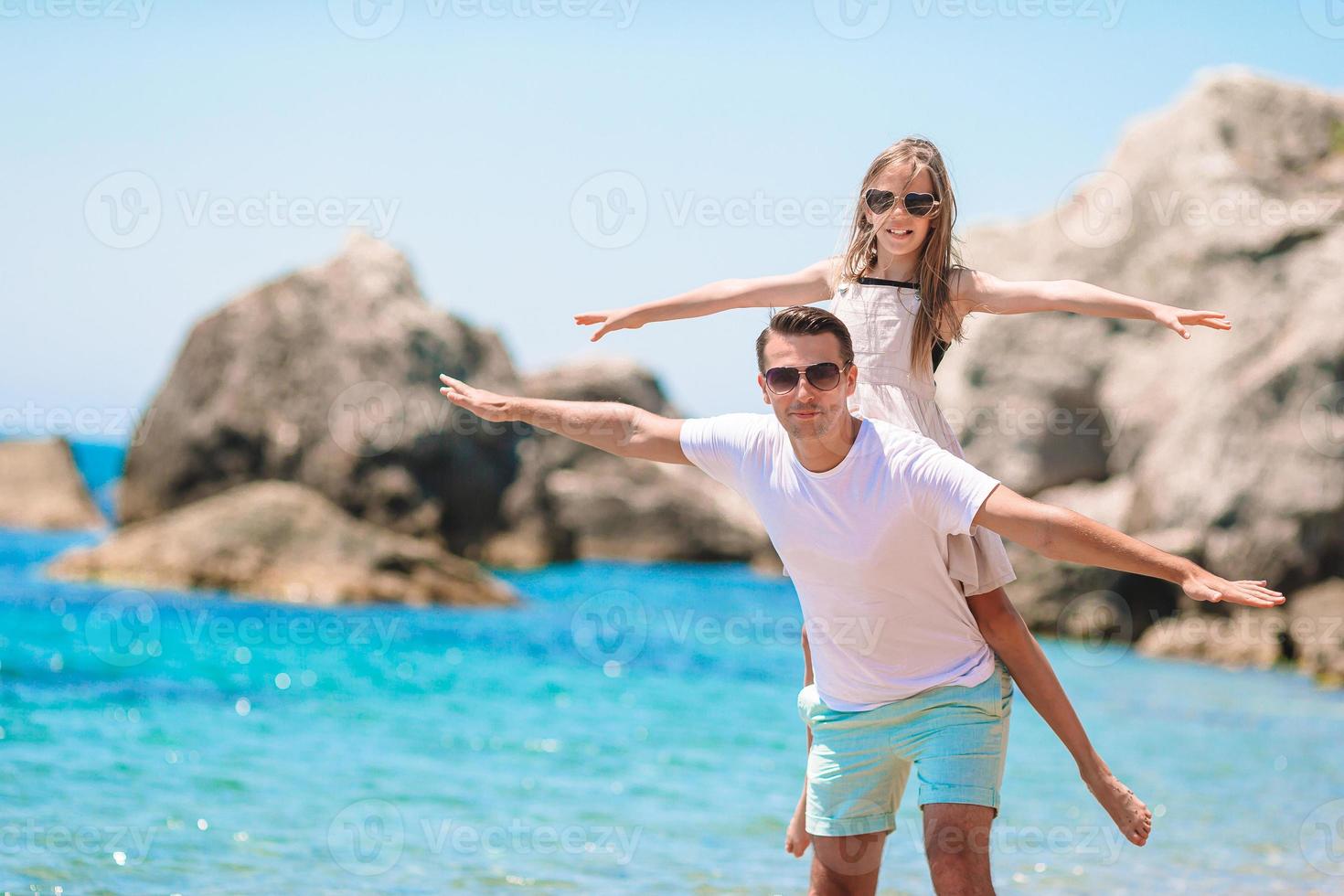 menina e pai feliz se divertindo durante as férias na praia foto