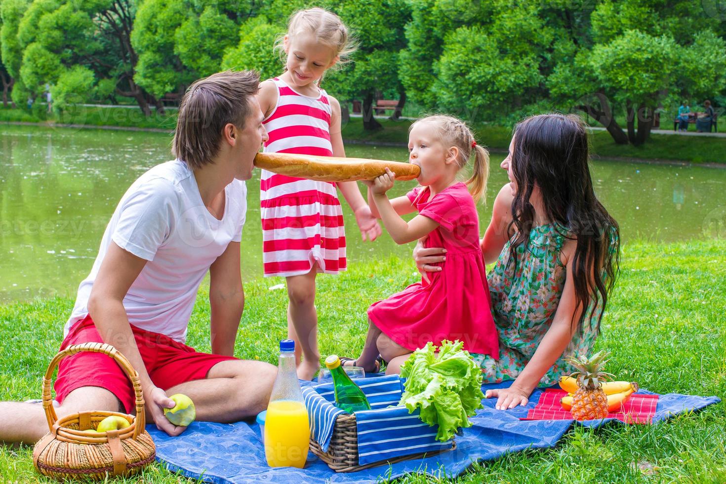 família de quatro pessoas faz piquenique no parque num dia de verão foto