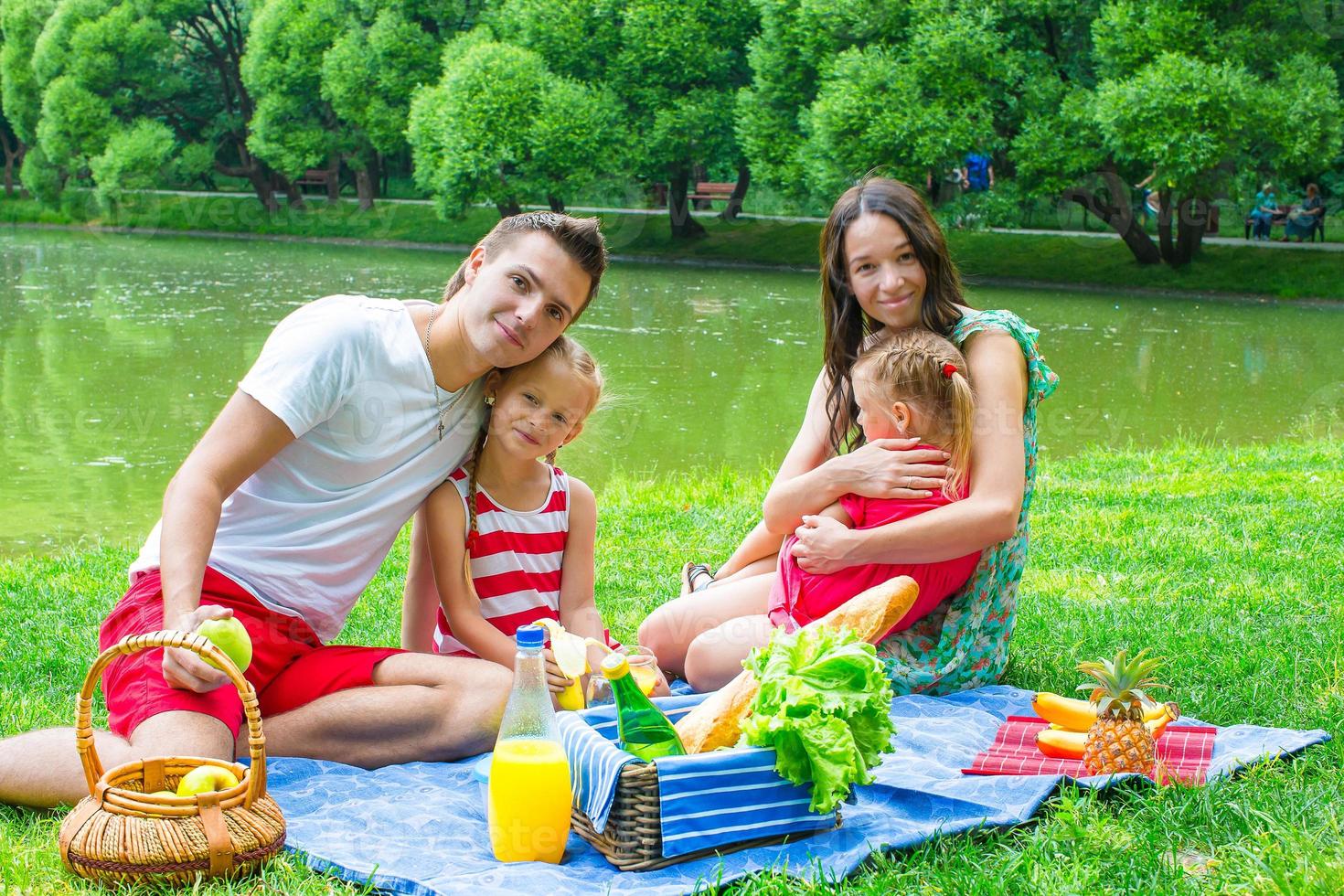 família jovem feliz, um piquenique ao ar livre perto do lago foto