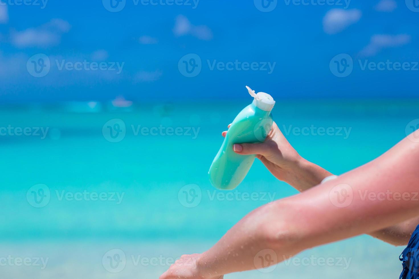 mão de mulher colocando protetor solar de um frasco de creme solar foto
