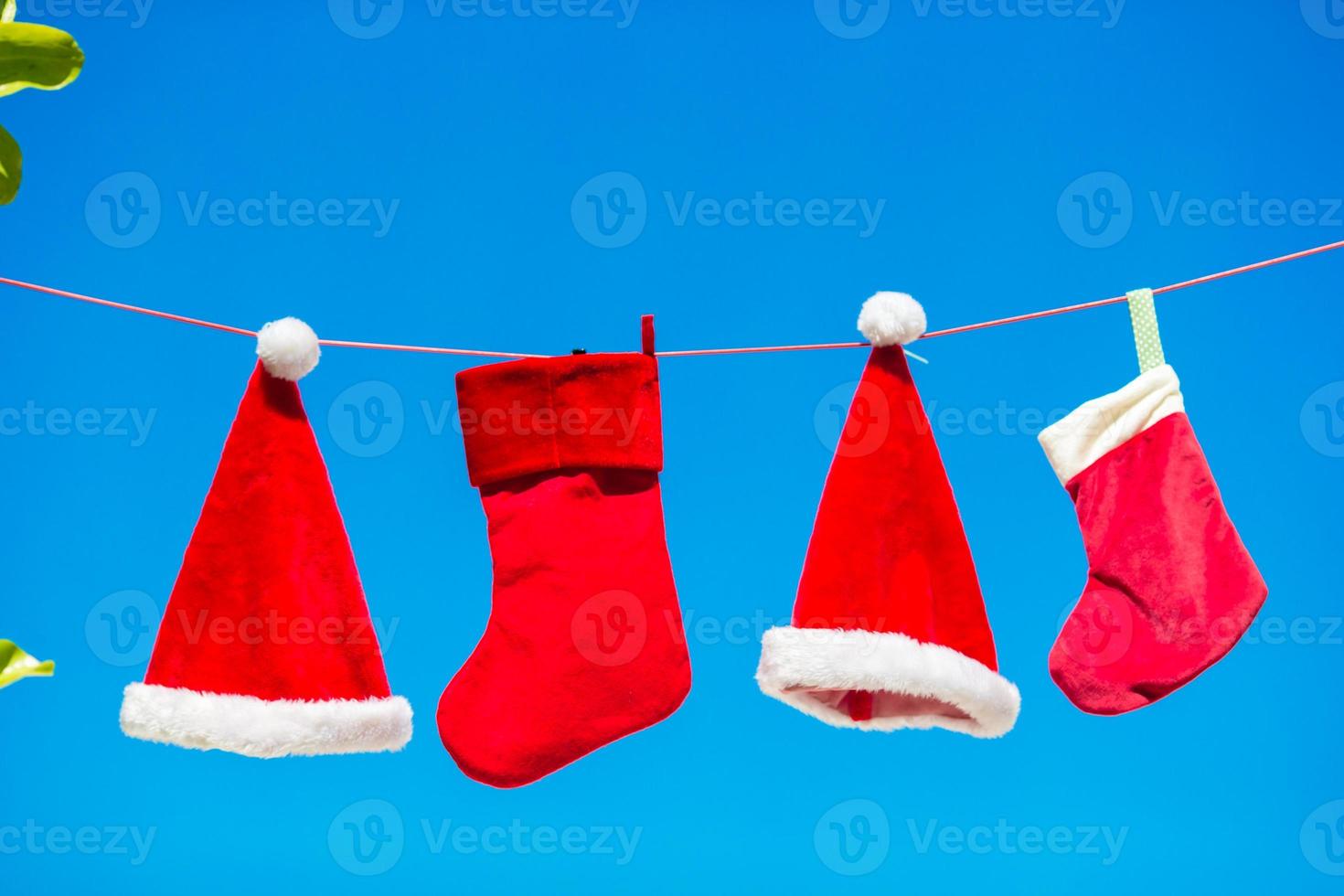 chapéus de papai noel vermelhos e meia de natal entre palmeiras na praia branca foto