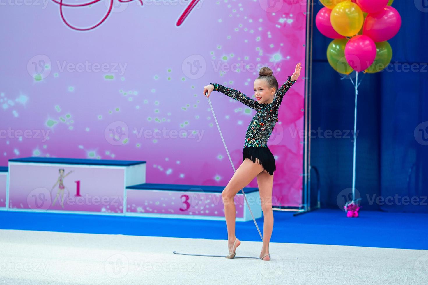 linda garotinha ginasta no tapete da competição foto