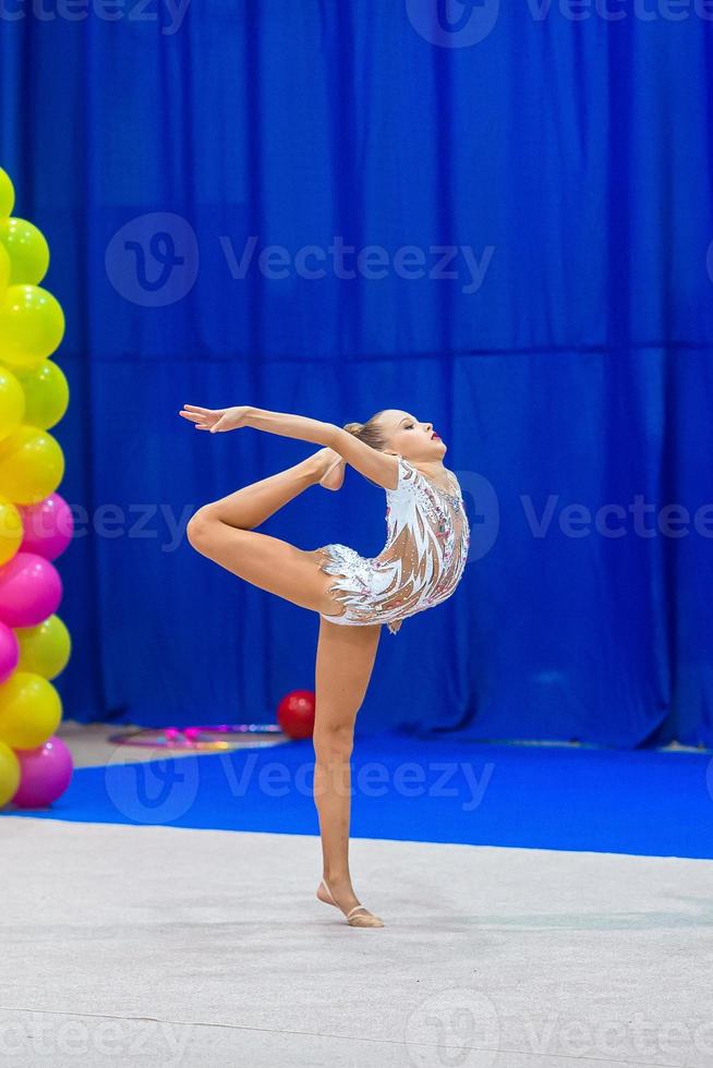 linda garotinha ginasta no tapete da competição foto