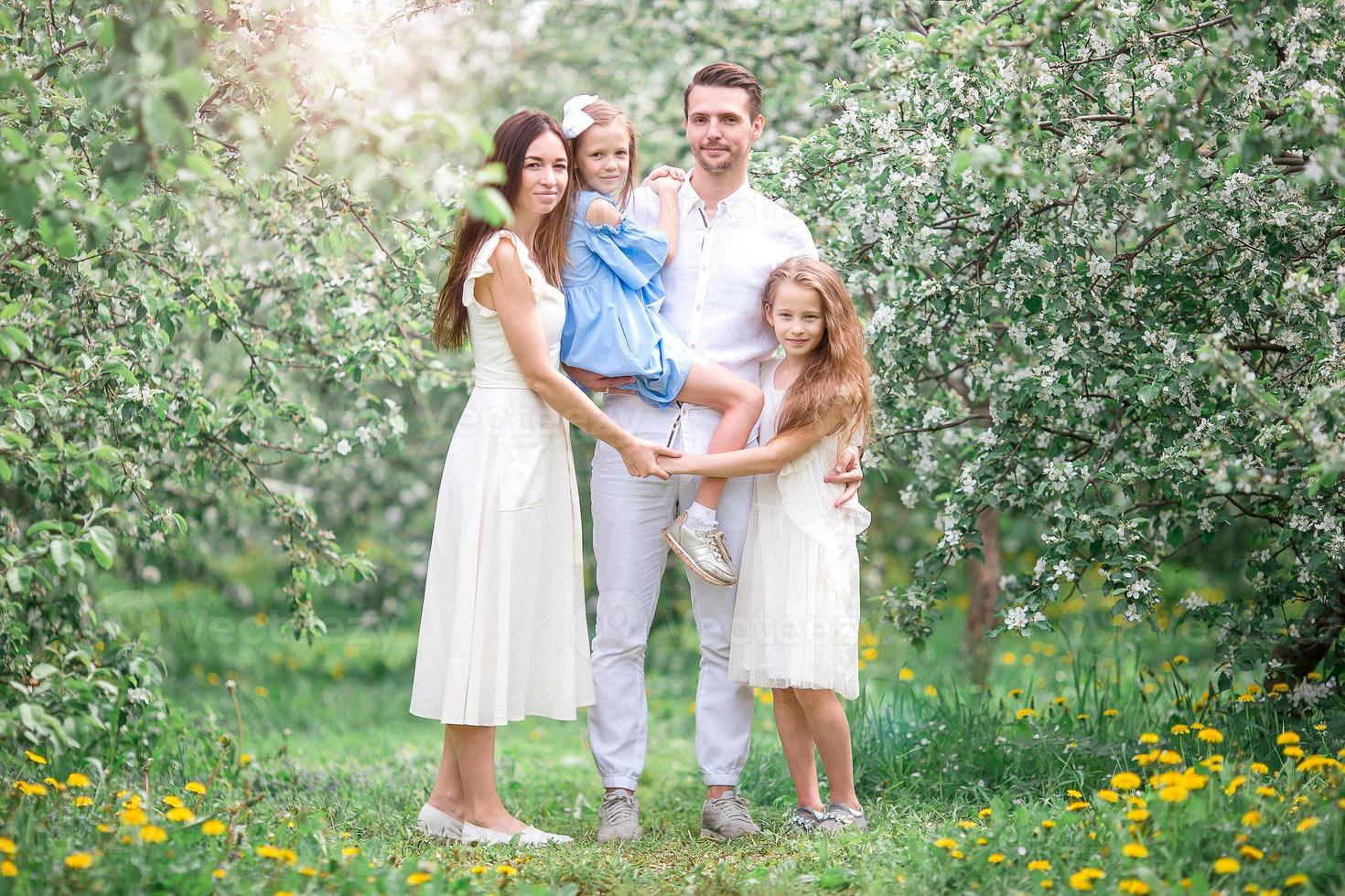 família adorável no jardim cerejeira florescendo em lindo dia de primavera foto