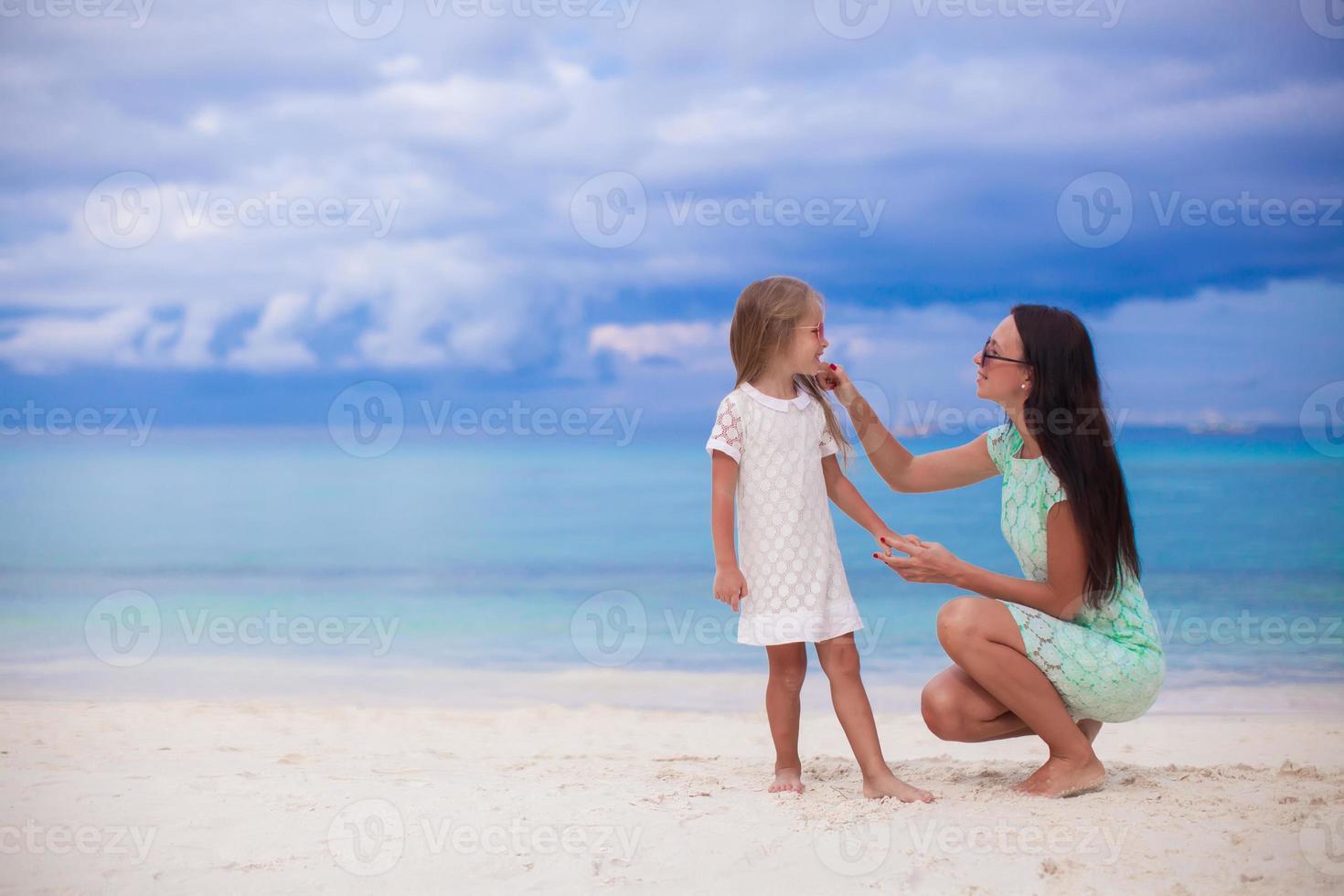 menina e sua jovem mãe relaxam na praia foto