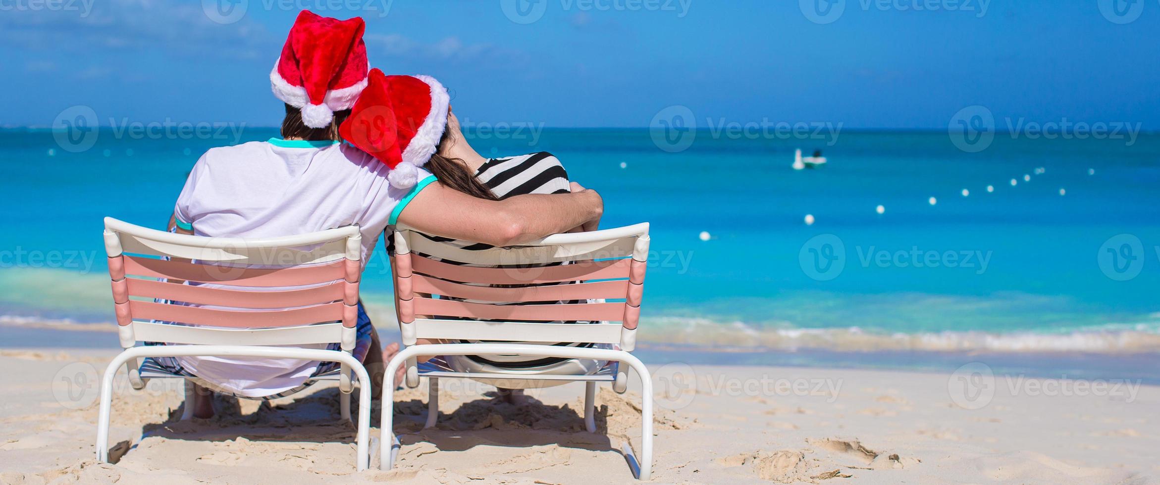 jovem casal romântico em chapéus de Papai Noel durante as férias na praia foto
