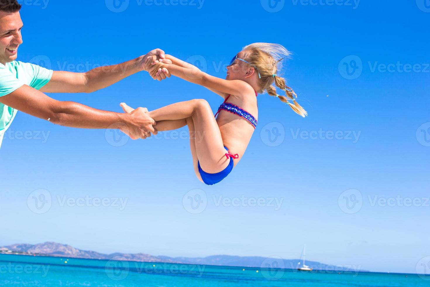 menina feliz se diverte com o pai durante as férias na praia foto