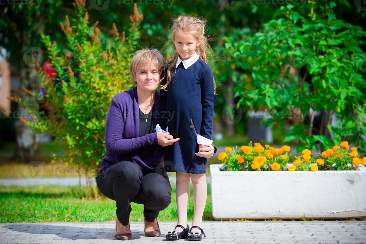 avó traz a neta para a escola. adorável menina se sentindo muito animada em voltar para a escola foto