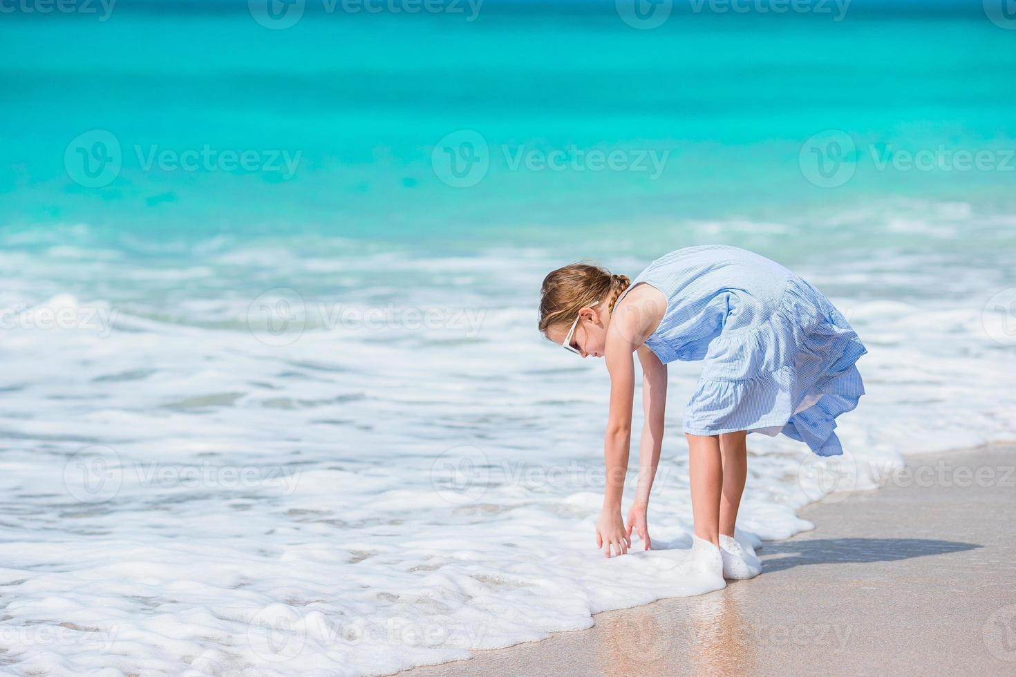 adorável menina na água rasa. linda criança lavando as mãos na onda foto