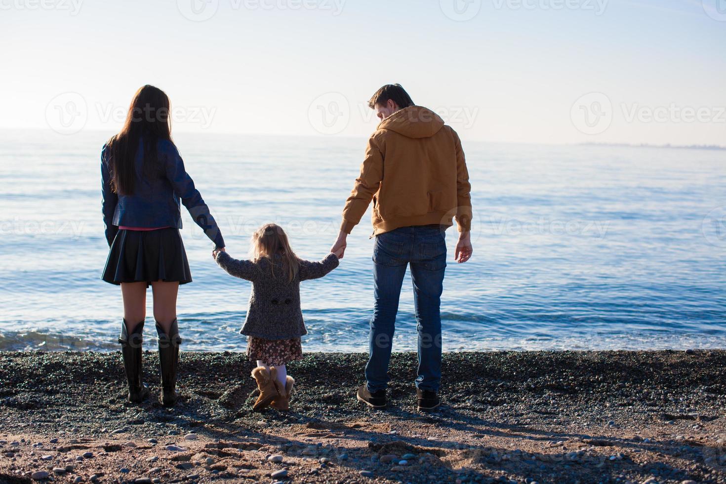 família na praia selvagem durante o inverno quente foto