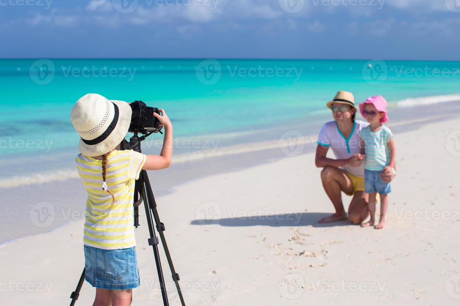 menina fazendo foto de seu pai e irmã na praia