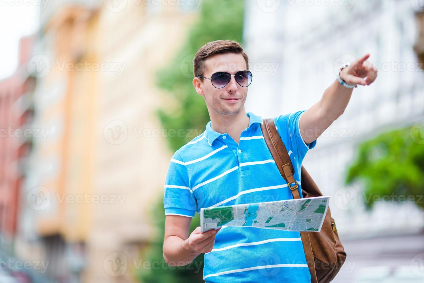 homem turista com um mapa da cidade e mochila na Europa. menino caucasiano olhando o mapa da cidade europeia em busca de atrações. foto