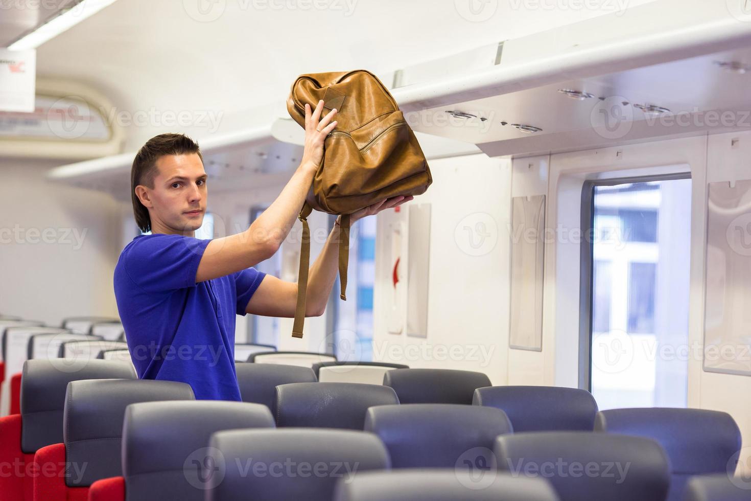 jovem colocando bagagem no armário superior no trem foto