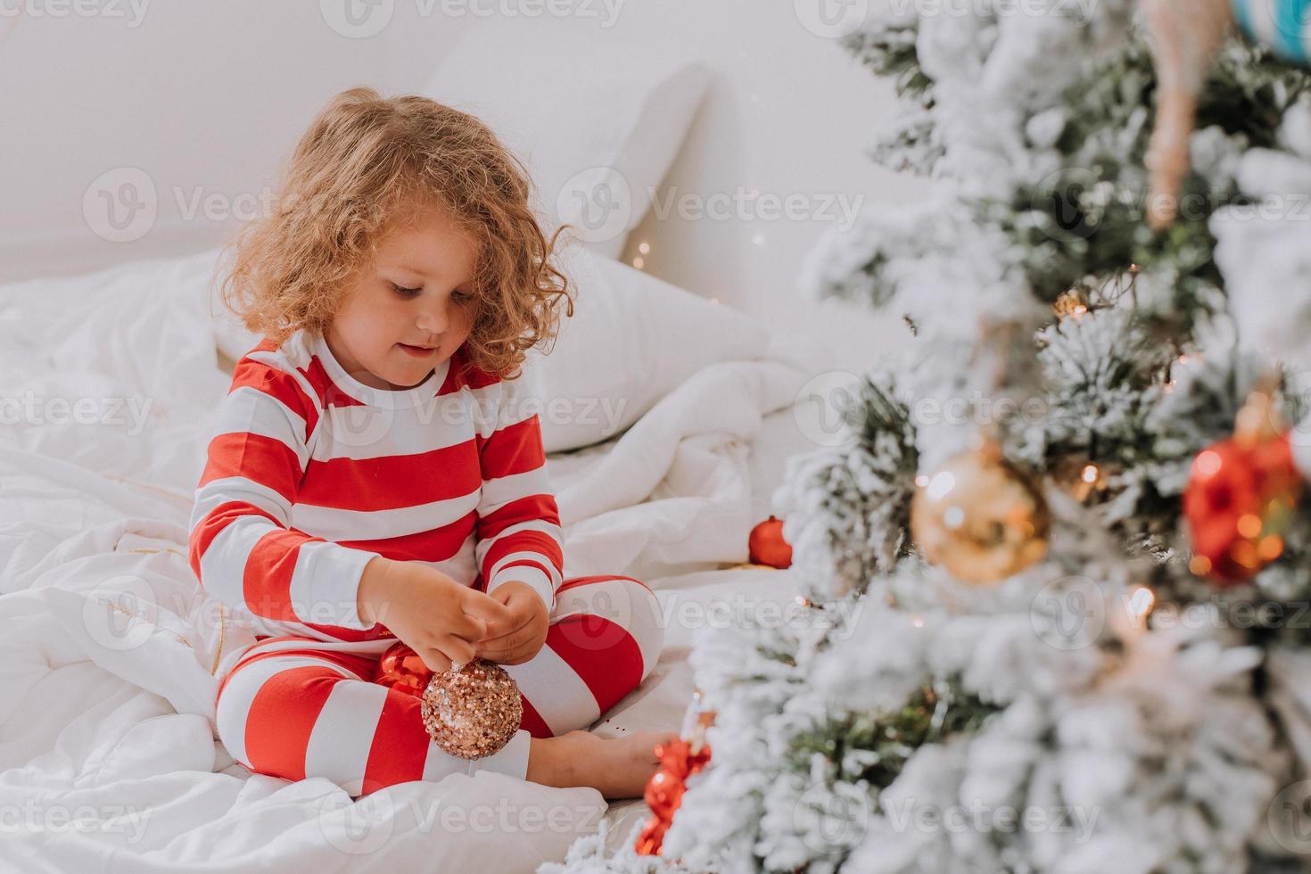 menina de pijama listrado de natal decora a árvore de natal. estilo de vida. foto de alta qualidade