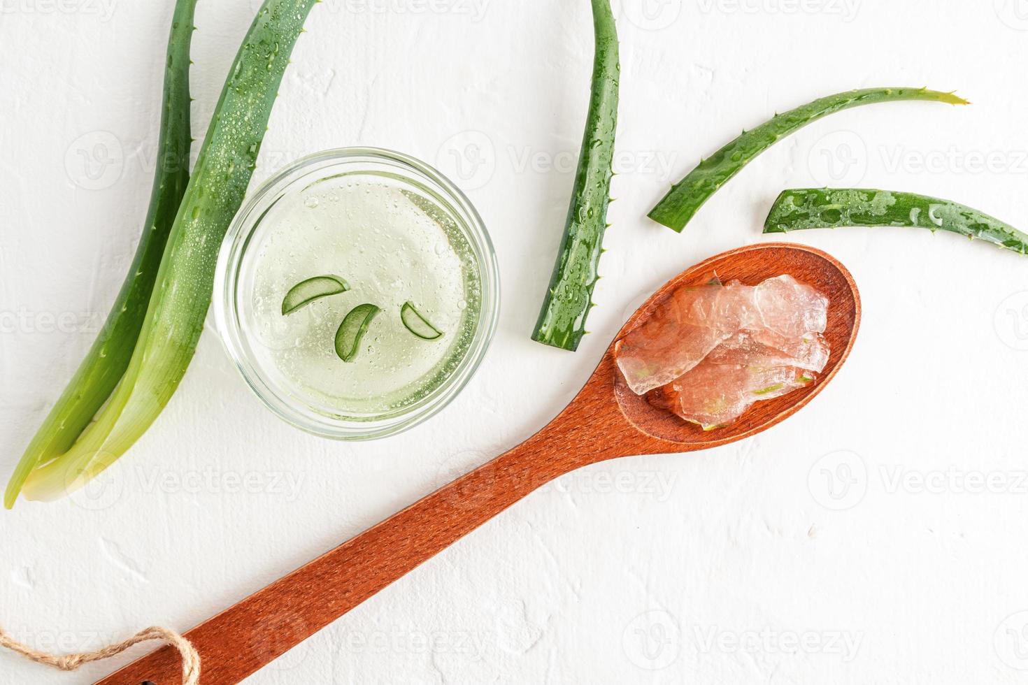 exstrate gel orgânico de aloe vera em uma colher de pau em um fundo branco. as folhas da planta na tigela de vidro. autocuidado cosmético. foto