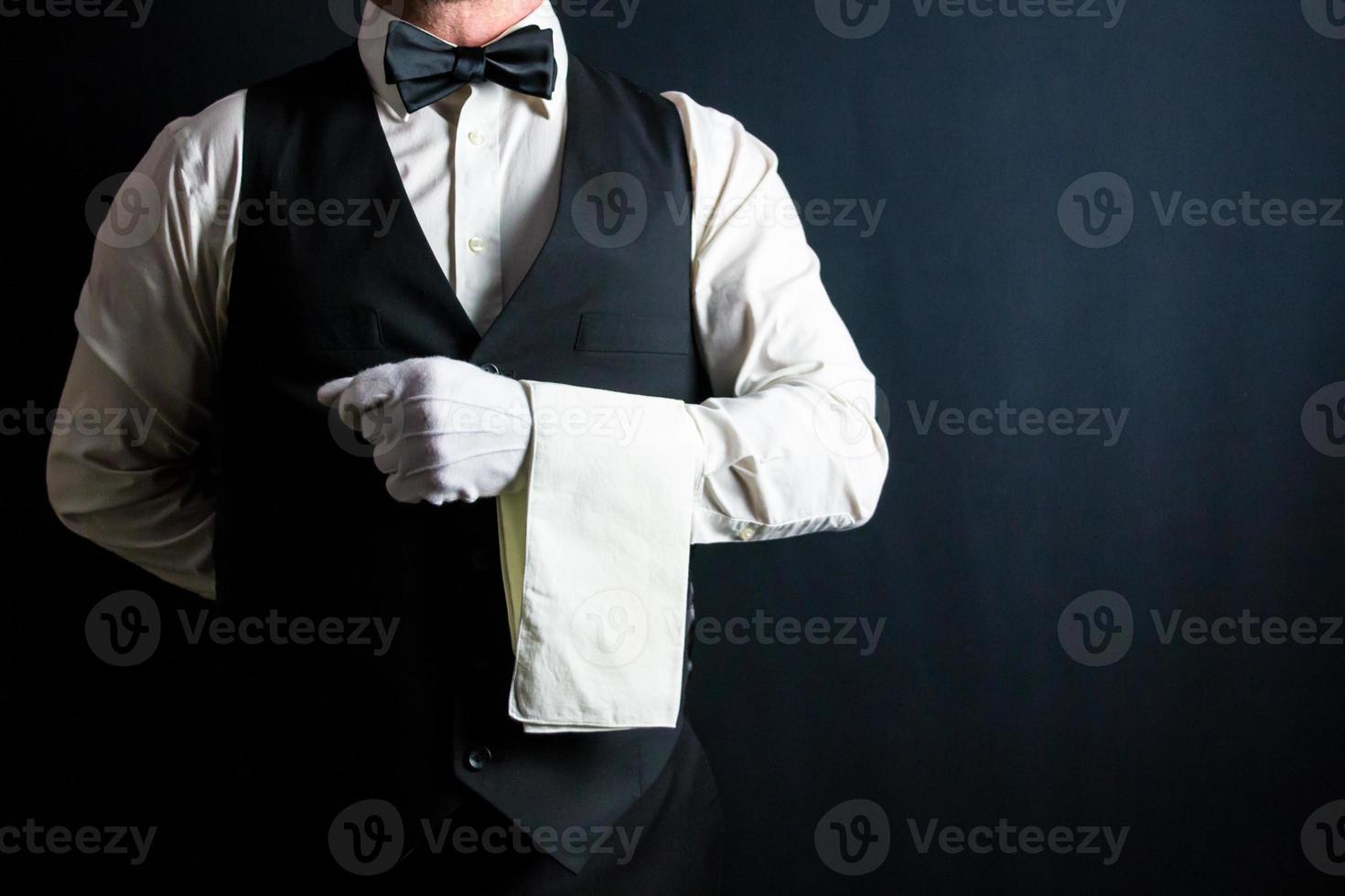 retrato de mordomo ou garçom de colete preto e luvas brancas e guardanapo dobrado sobre o braço. indústria de serviços e hospitalidade profissional. foto