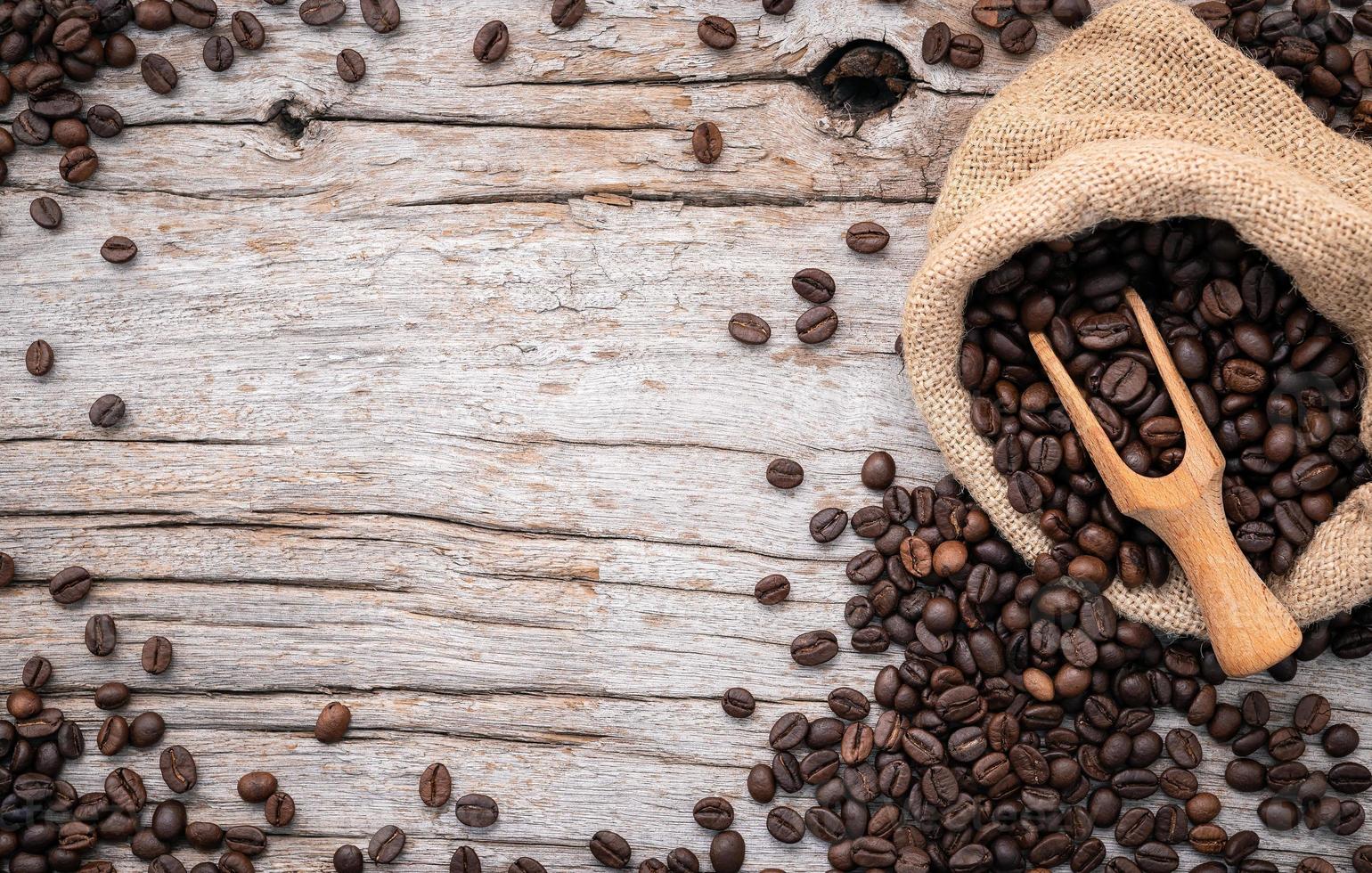 fundo de grãos de café torrados escuros com colheres configurados em fundo de madeira com espaço de cópia. foto