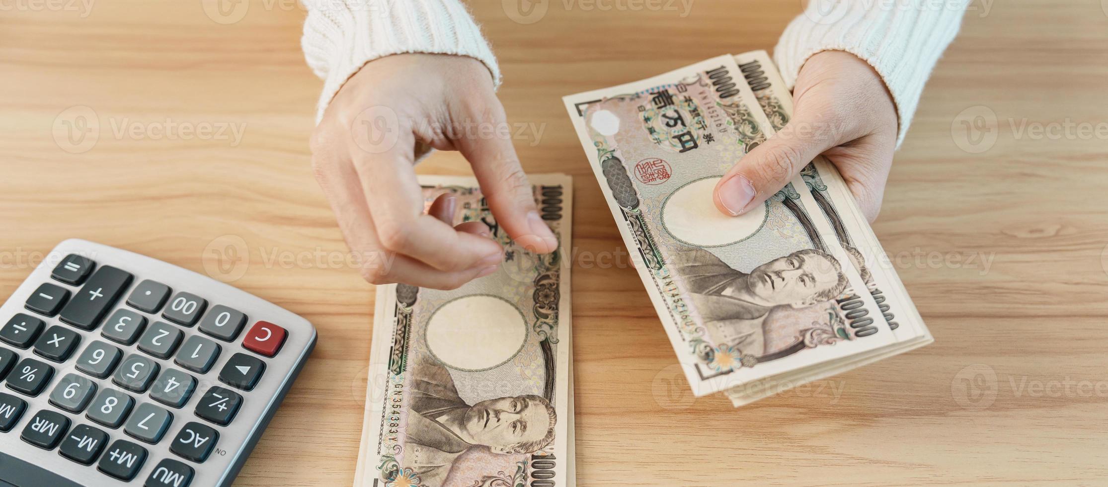 mão de mulher contando notas de iene japonês com calculadora. dinheiro de mil ienes. dinheiro do japão, imposto, economia de recessão, inflação, investimento, finanças, poupança, salários e conceitos de pagamento foto