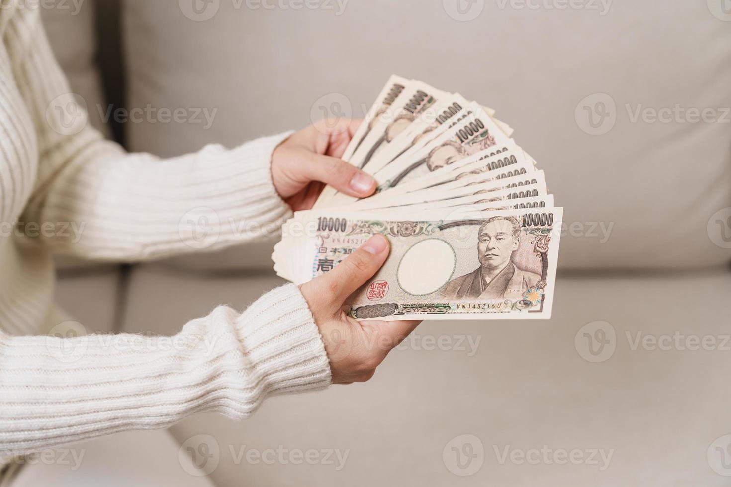 mão de uma mulher segurando a pilha de notas de iene japonês. dinheiro de mil ienes. dinheiro do japão, impostos, economia de recessão, inflação, investimento, finanças e conceitos de pagamento de compras foto