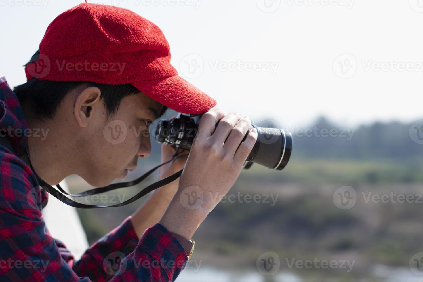 menino asiático está usando binóculos para observar os pássaros na floresta tropical durante o acampamento de verão, ideia para aprender criaturas e animais selvagens e insetos fora da sala de aula. foto