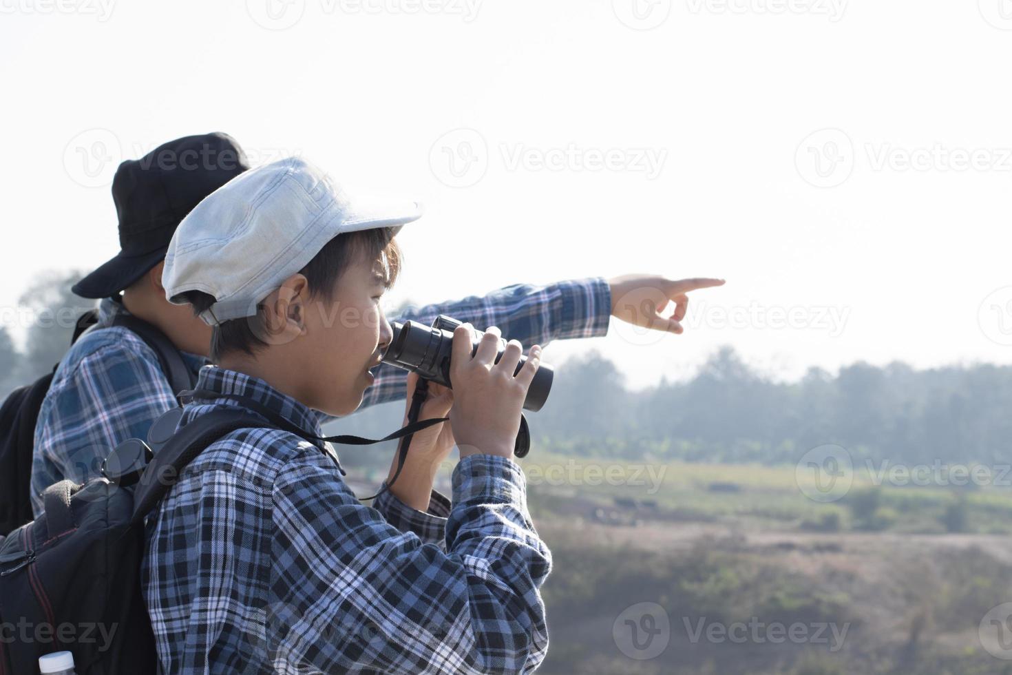 meninos asiáticos estão usando binóculos para observar os pássaros na floresta tropical durante o acampamento de verão, ideia para aprender criaturas e animais selvagens e insetos fora da sala de aula. foto