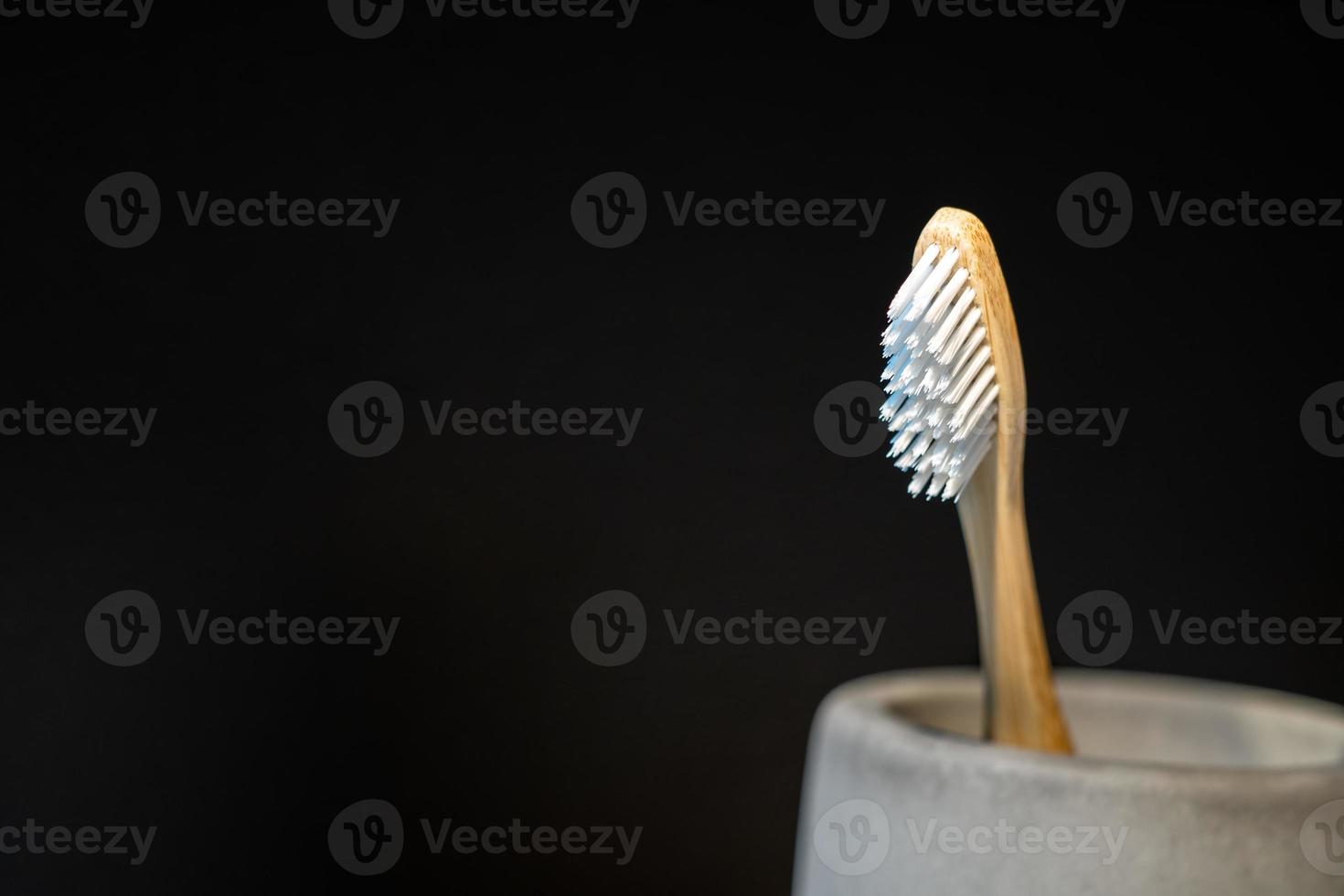 closeup de escova de dentes de madeira na caneca e na frente de fundo preto. foto