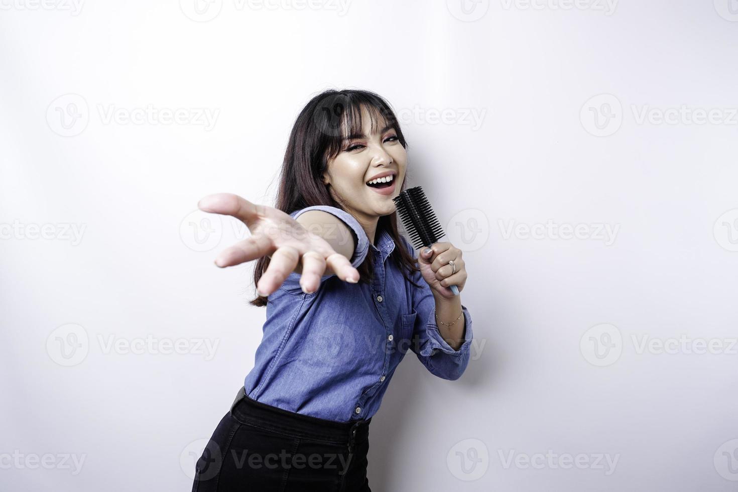 retrato de mulher asiática despreocupada, se divertindo karaokê, cantando no microfone em pé sobre fundo branco foto