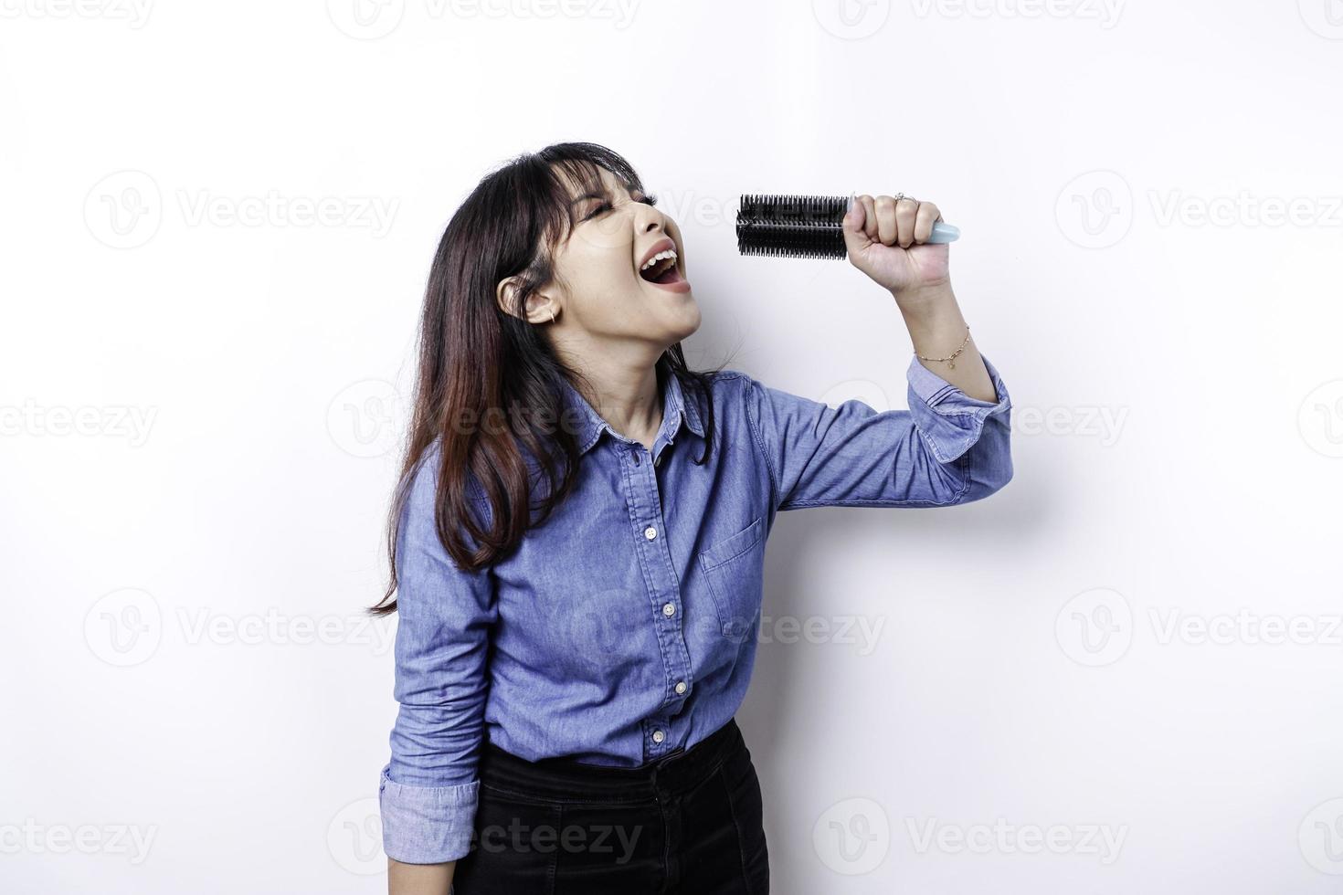 retrato de mulher asiática despreocupada, se divertindo karaokê, cantando no microfone em pé sobre fundo branco foto